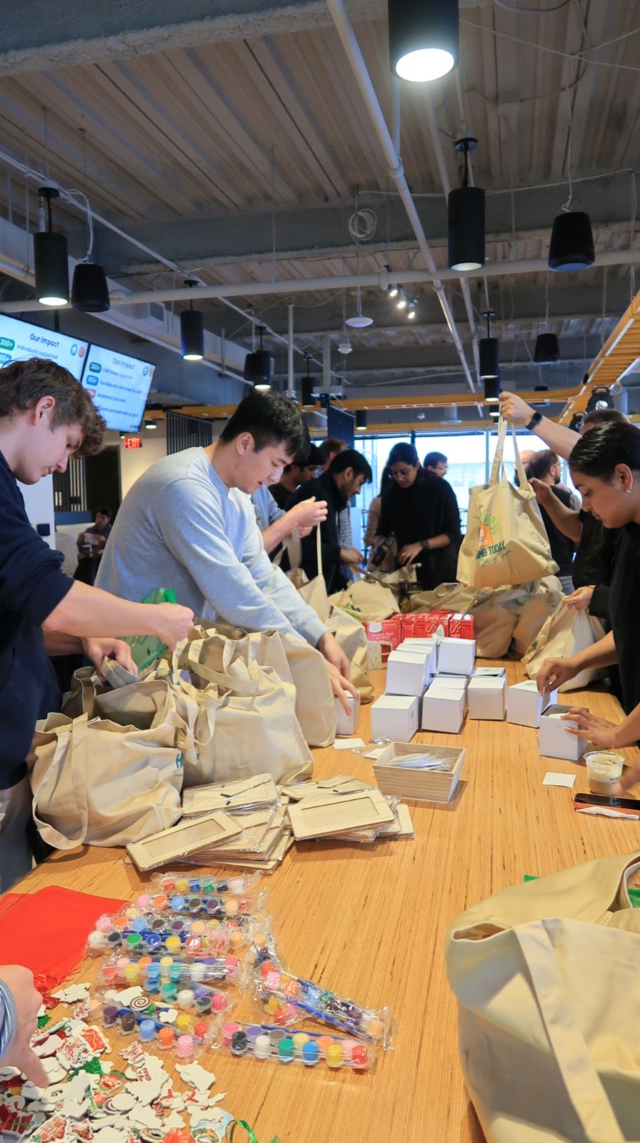 Hive team volunteering, packing tote bags at a long wooden table