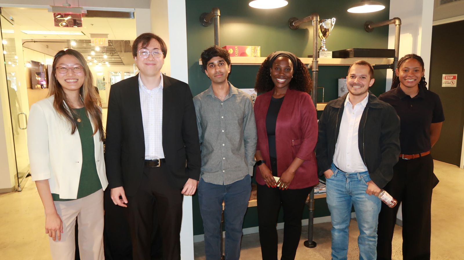 Six Hive team members standing together in front of the green wall at the Atlanta office